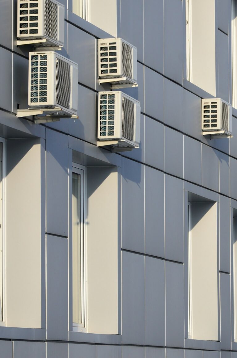 Gray wall of office building made of metal plates with windows and air conditioners